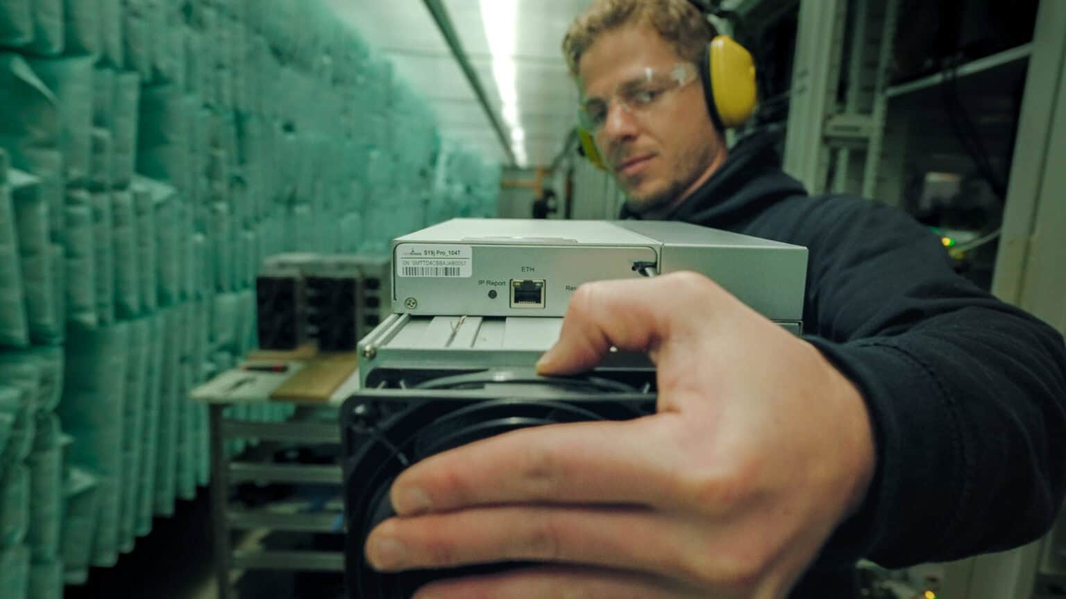 Technicien qualifiÃƒÂ© effectuant la maintenance d'un miner ASIC dans une ferme de minage, garantissant des rÃƒÂ©parations rapides et une durÃƒÂ©e de vie prolongÃƒÂ©e du matÃƒÂ©riel de mining.
